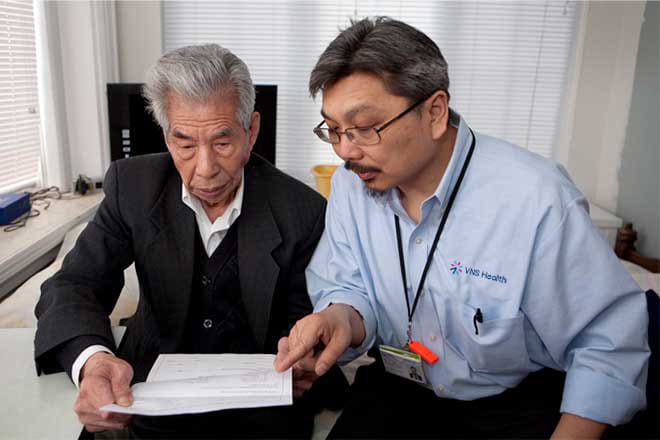 vns health team member pointing at paperwork for senior man