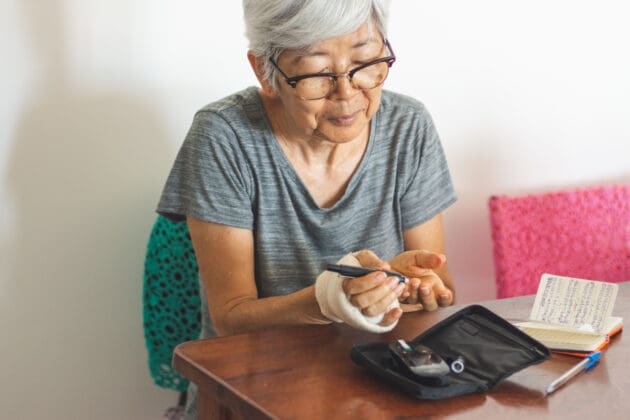 Senior woman with glucometer checking blood sugar level at home.