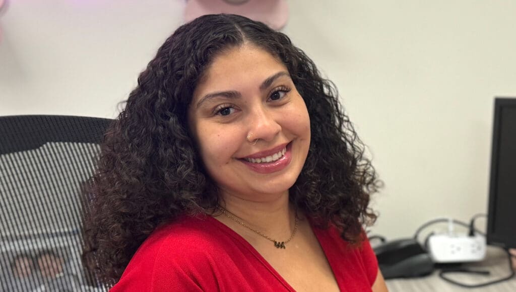 photo of program assistant Gabby sitting in office and smiling